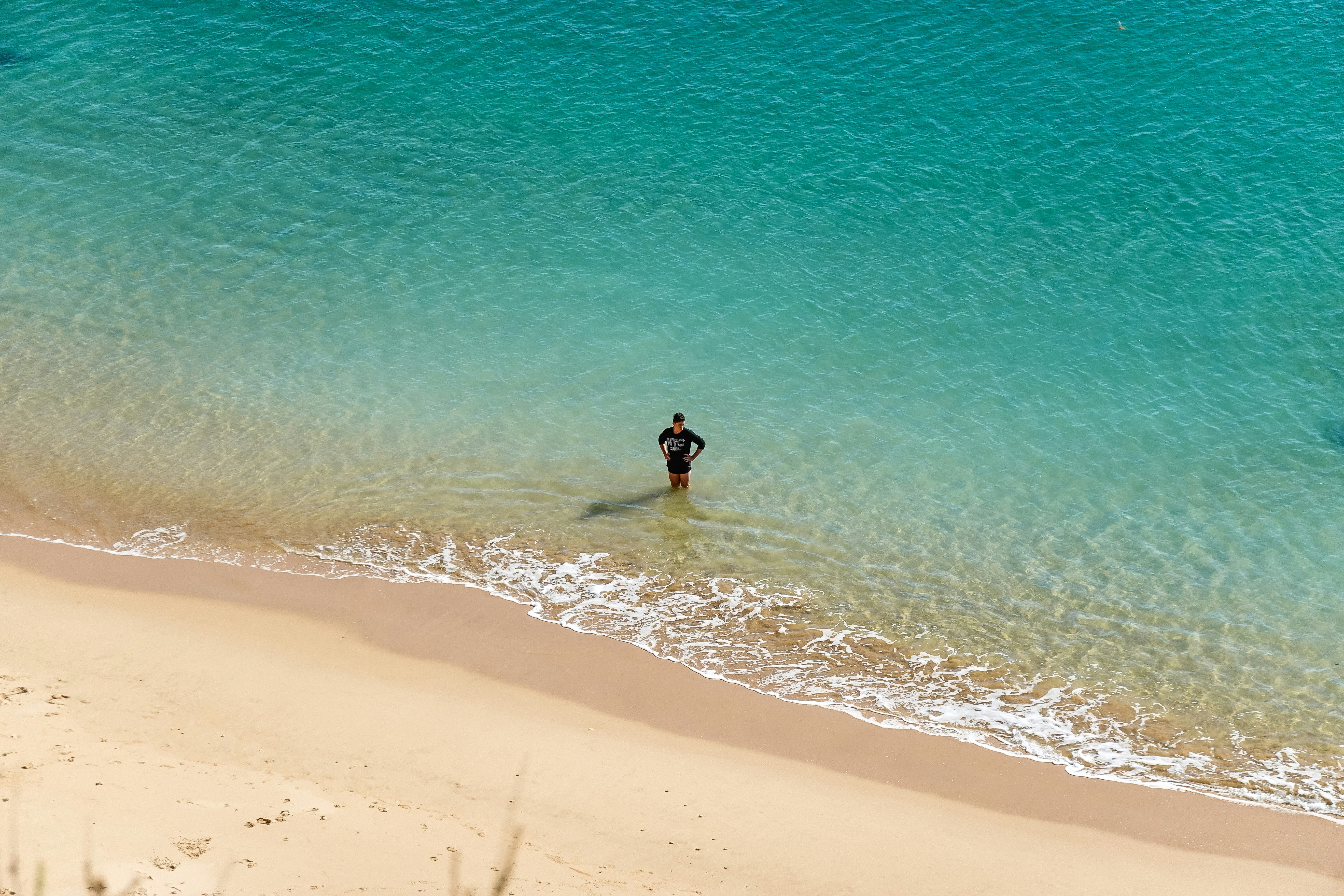 person in black wet suit walking on beach during daytime